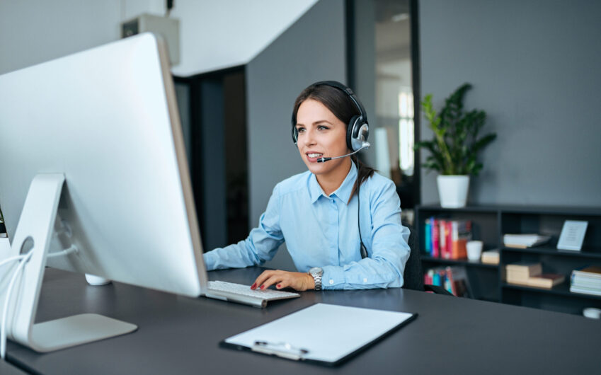 Helpdesk and support concept. Young elegant woman with headset working on computer.